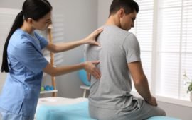 Orthopedist Examining Man's Back In Clinic. Scoliosis Treatment