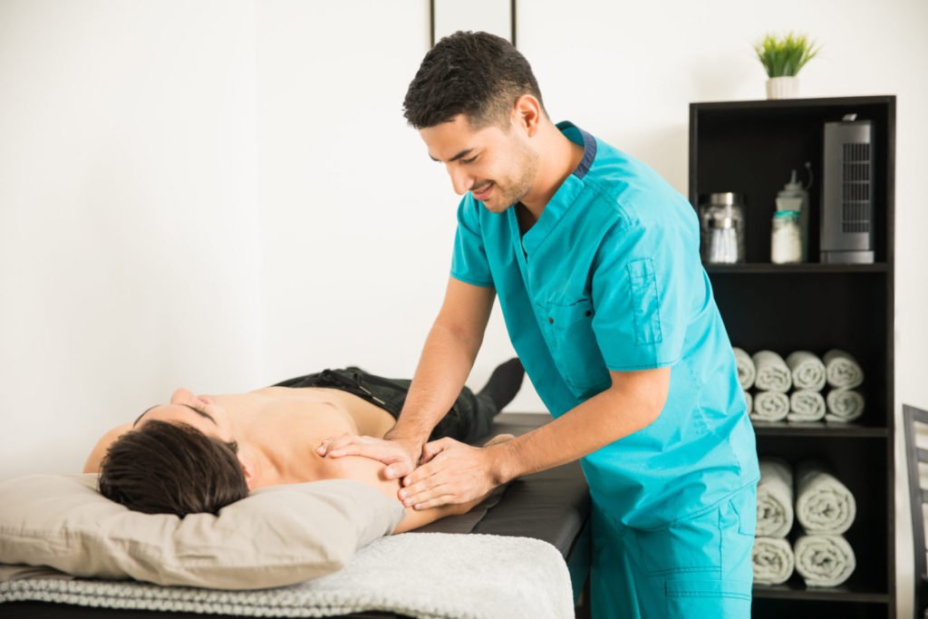 Therapist Massaging The Injured Shoulder Of Athlete In Hospital
